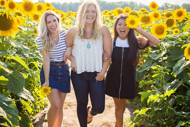 3 girls smiling in sunflowers field
