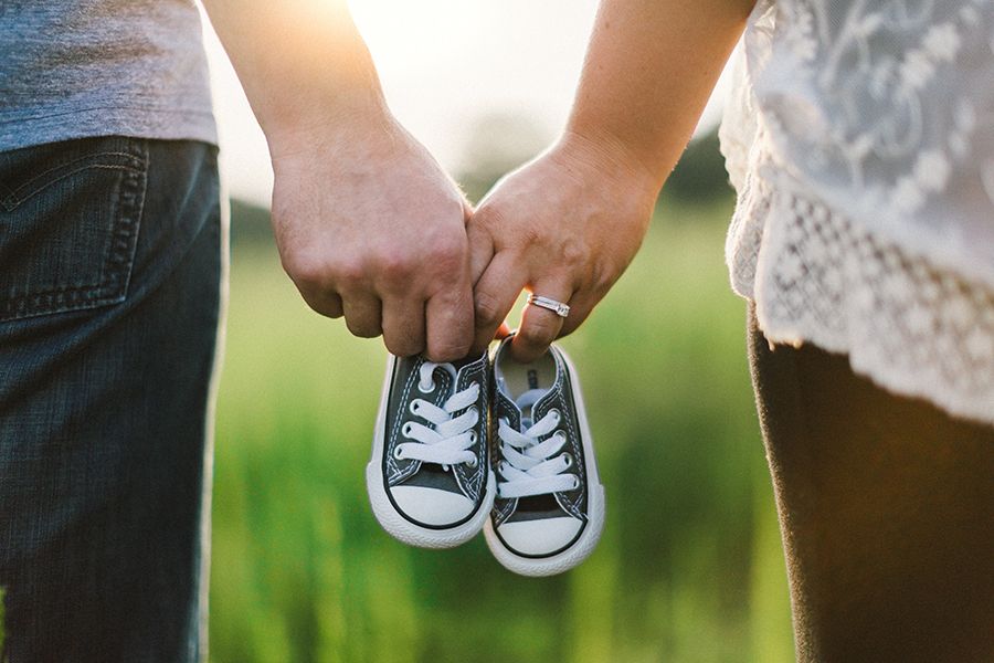 Parents holding hands and baby shoes